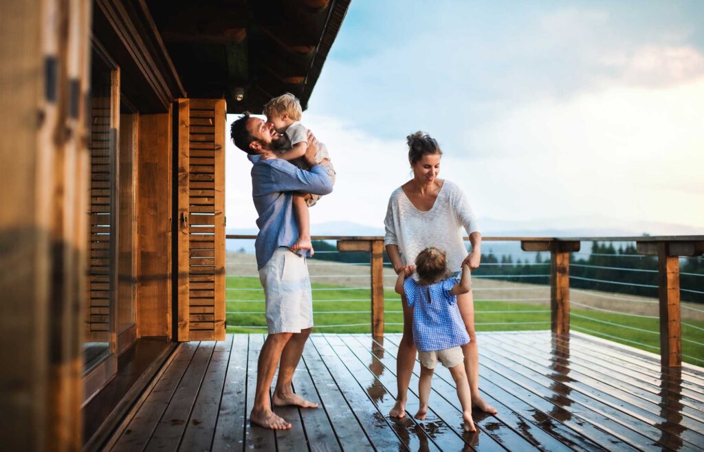 Family with small children playing in rain on patio